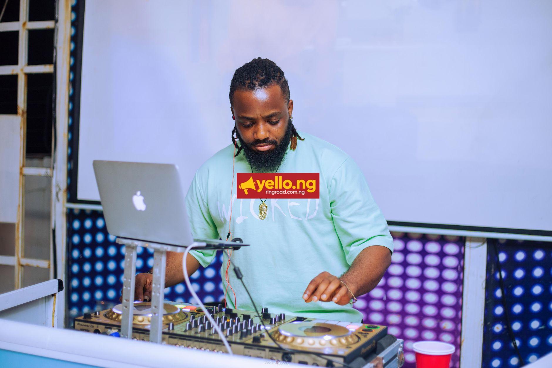 DJ performing at a live indoor music event in Lagos Nigeria with mixer and MacBook laptop
